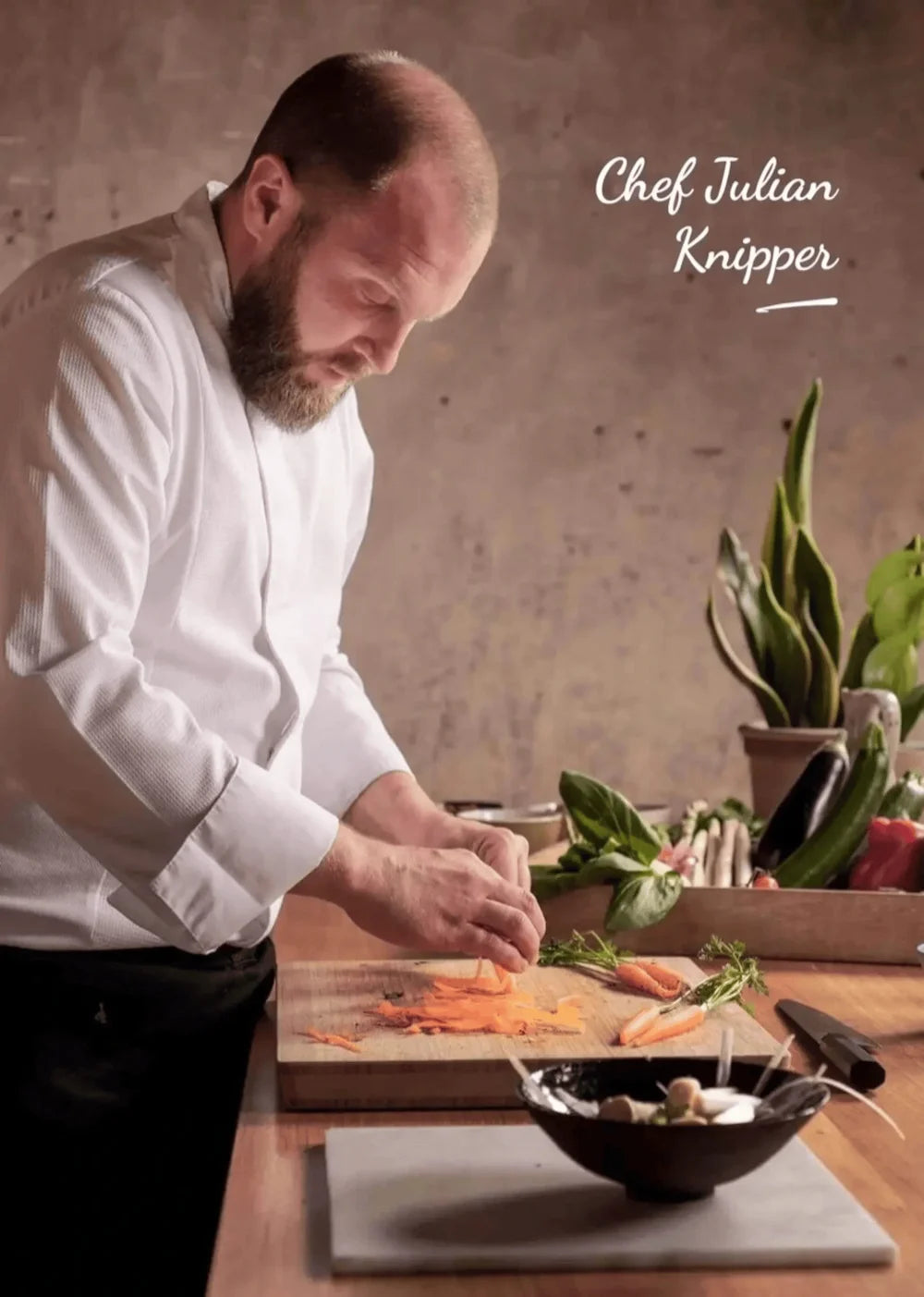 Chef Julian Knipper en train de découper des légumes sur une planche de bois